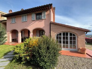 Ein zweigeschossiges Haus mit Ziegelverkleidung, Rundbogenfenstern und einem Schotterweg.