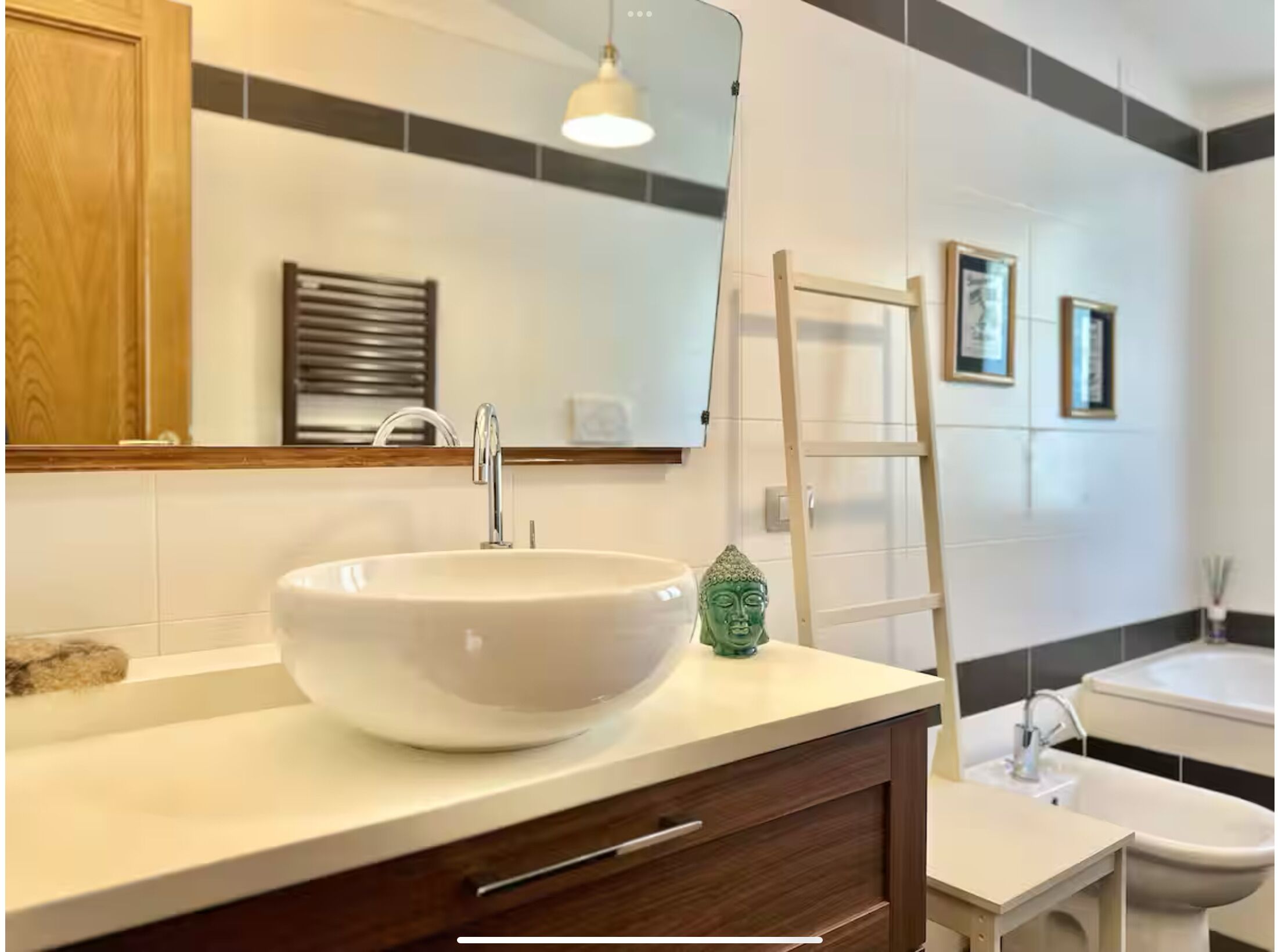 Un baño moderno con un lavamanos grande de color blanco, un mueble de tocador de madera, un espejo y un perchero para toallas.