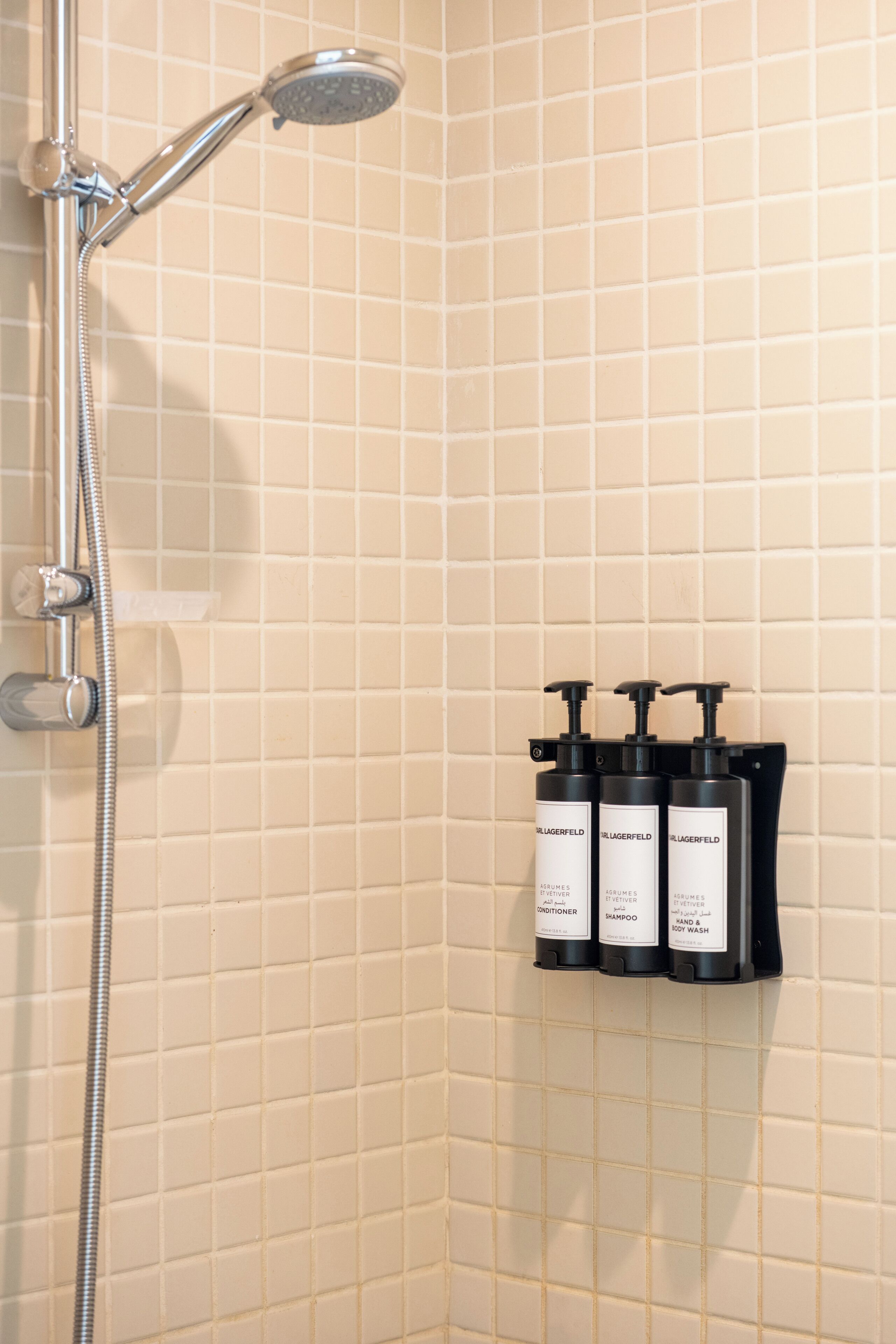 Un espace douche équipé d’un pommeau de douche à main et d’un sèche-mains fixé au mur.