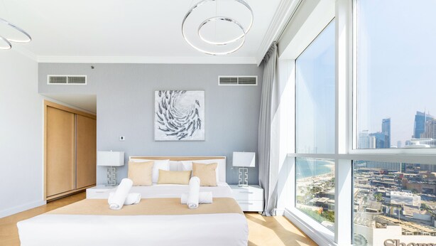 A modern hotel room with a large bed, two bedside tables with lamps, a city view, and a large window. - Al Bateen I Ultra Luxury I Private Beach (Dubai)