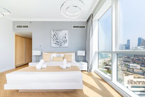 A modern hotel room with a large bed, two bedside tables with lamps, a city view, and a large window. - Al Bateen I Ultra Luxury I Private Beach (Dubai)