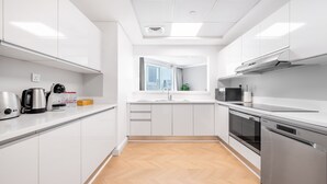 A modern kitchen with white cabinets, stainless steel appliances, and a herringbone wood floor. - Al Bateen I Ultra Luxury I Private Beach (Dubai)