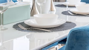 A dining table set with white plates, bowls, and wine glasses, accompanied by a vase of white orchids and candles. - Al Bateen I Ultra Luxury I Private Beach (Dubai)