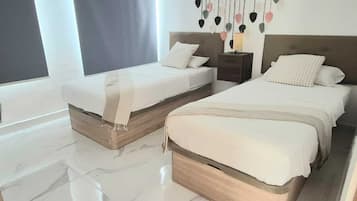 A modern bedroom with two beds, a nightstand, and a wall-mounted light fixture.