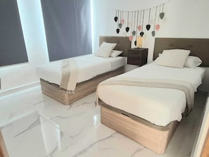 Een moderne slaapkamer met twee bedden, een nachtkastje en een wandlamp.