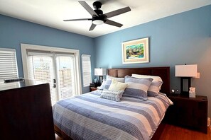 A bedroom with a bed, a ceiling fan, a nightstand, a lamp, and a window with blinds. - Charming 2 BR house with pool and hot tub walking distance to the beach/Las Olas (Fort Lauderdale)