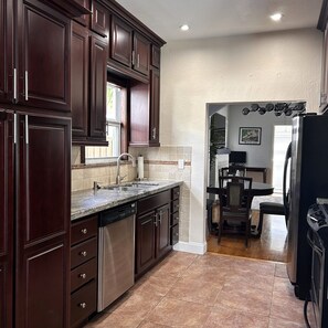 Una cocina con armarios de madera oscura, electrodomésticos de acero inoxidable y un salpicadero de azulejos.