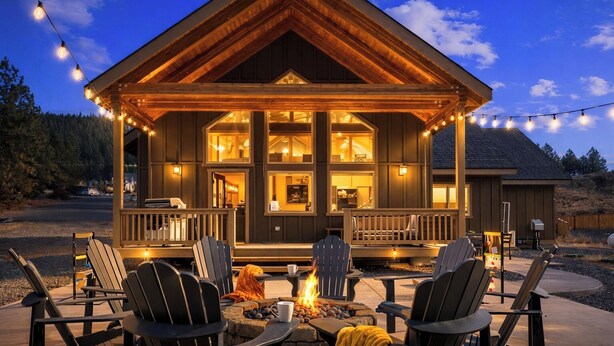 Une cabane en bois avec une véranda, un espace salon extérieur et un foyer.
