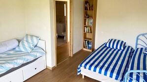 Une chambre avec deux lits, une bibliothèque en bois et une porte donnant sur une salle de bain.