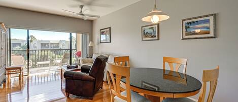 A dining area with a round table, wooden chairs, and a ceiling fan.