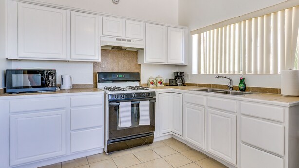 A modern kitchen with white cabinets, a stove, a microwave, and a sink. - Lake Elsinore Apt 4 Mi to Water: Pets Welcome! (Lake Elsinore)