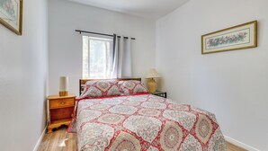 A bedroom with a bed, a nightstand, a lamp, a window with curtains, and a framed picture on the wall. - Lake Elsinore Apt 4 Mi to Water: Pets Welcome! (Lake Elsinore)