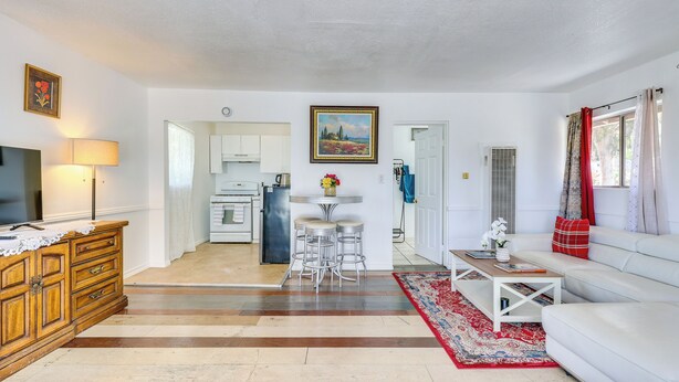 Un salon avec un canapé, une table basse, un téléviseur et, au fond, une cuisine.