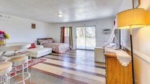 Une pièce spacieuse comprenant un lit, un canapé blanc, une table à manger avec des chaises et un buffet en bois.
