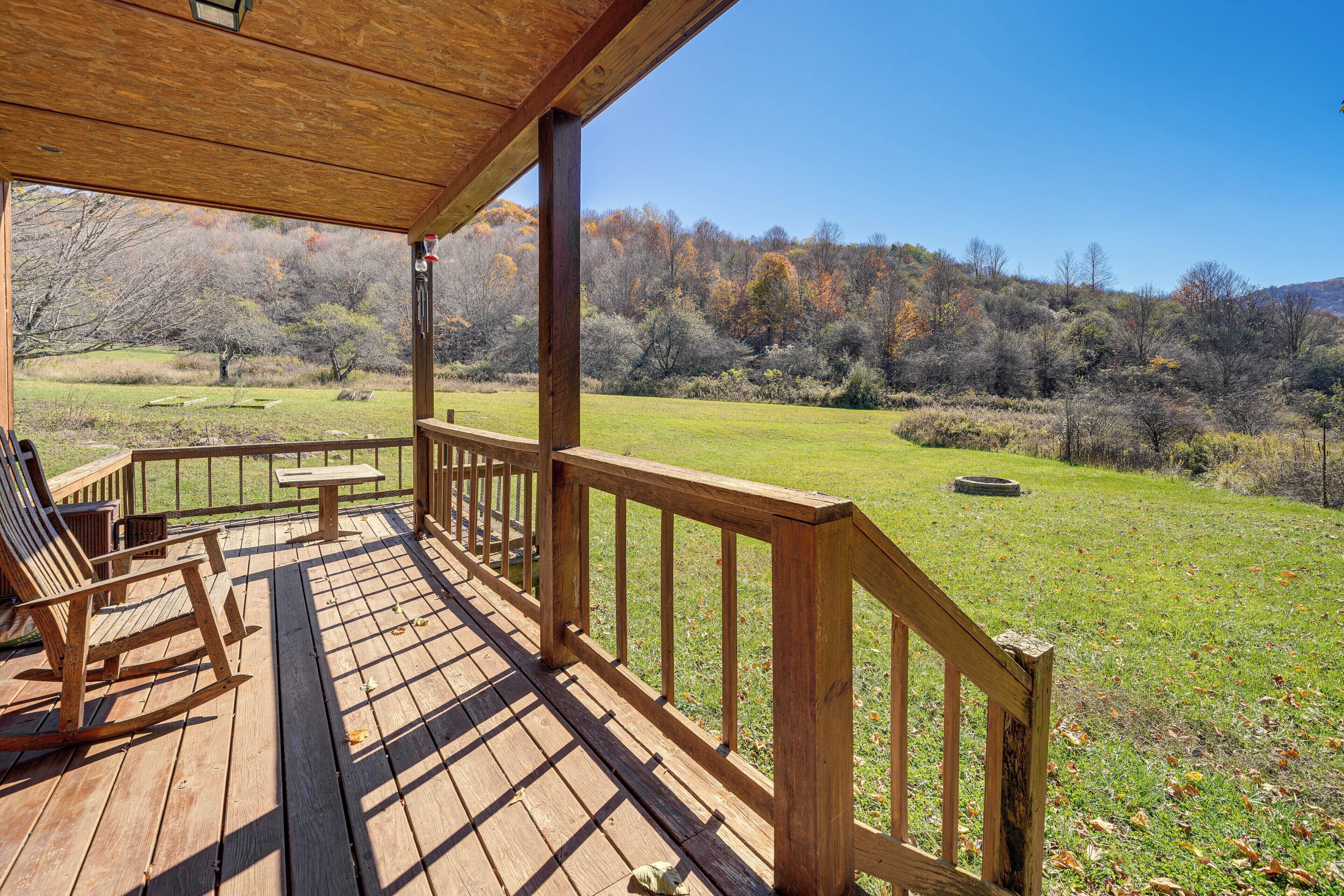 A wooden deck with a railing, a rocking chair, and a table.