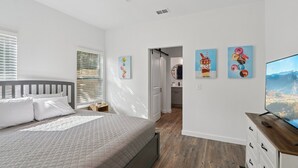A bedroom with a bed, a TV, and artwork on the wall.