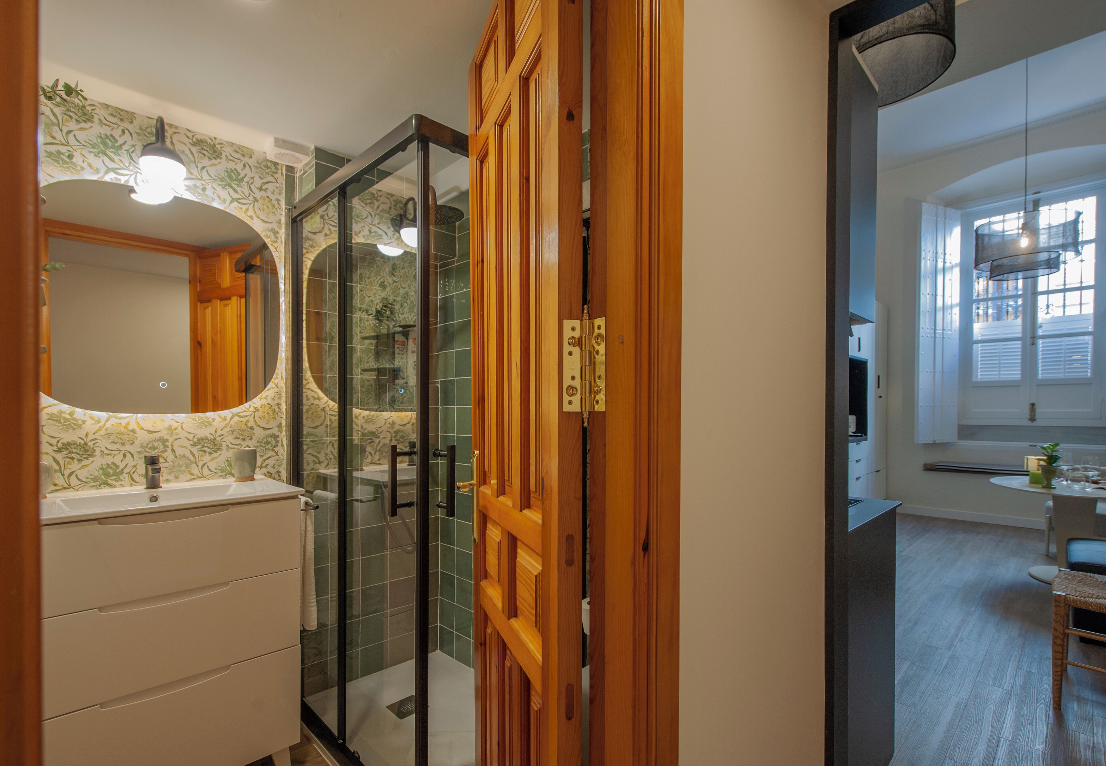 Ein modernes Badezimmer mit Duschkabine aus Glas, einer Holztür und einem weißen Waschbecken.