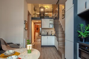A modern kitchen with a central island, built-in appliances, and a staircase leading to an upper level. - Seville Cathedral Suite (Sevilla)