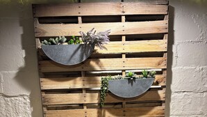Eine rustikale Wand mit Holzlatten und zwei Pflanzkästen mit Pflanzen.