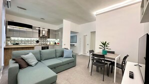 Un apartamento moderno con sala de estar, kitchenette, comedor y un balcón pequeño.