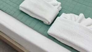 A neatly made bed with white pillows, a green quilted bedspread, and two folded white towels. - Alihouse lovely apartment in historic center 10 minutes from the station (Roma)