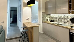 Una cocina moderna con una isla central, iluminación colgante y vista a otra habitación.