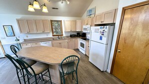 A kitchen with a central island, wooden cabinets, a white refrigerator, and a wooden door.