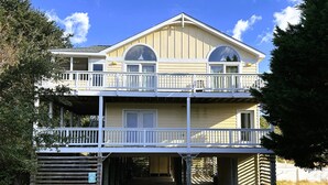 A two-story building with a balcony on the upper floor, a garage entrance, and a clear sky.