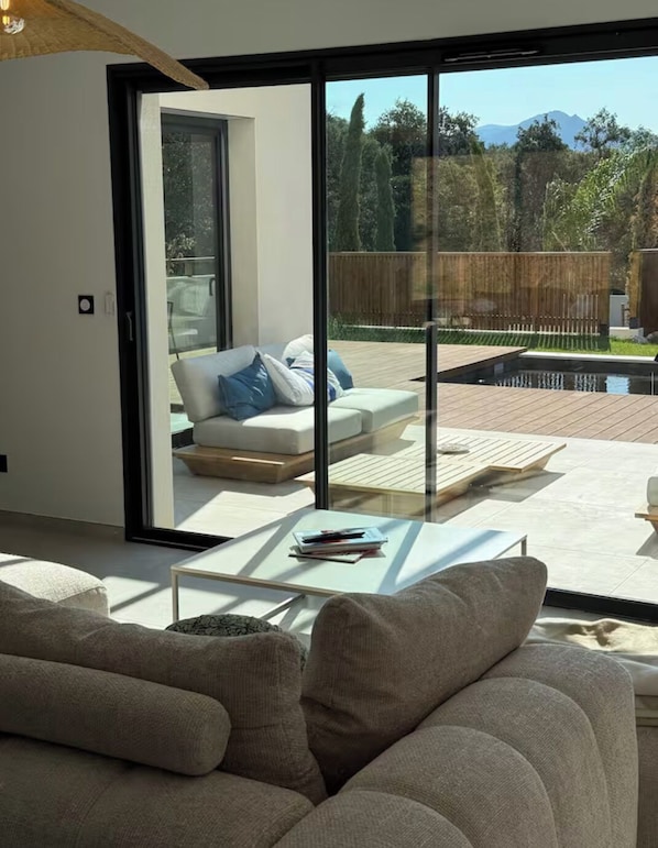 A modern living room with a sofa, a coffee table, and a sliding glass door leading to an outdoor deck.