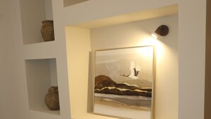 A wall with shelves displaying pottery and a framed painting. - Earthouse Rethymno (Rethimno)