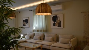 A modern living room with a sofa, a coffee table, and hanging wooden lamps. - Earthouse Rethymno (Rethimno)