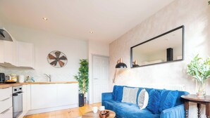 Uma sala de estar moderna com um sofá azul, uma mesa de centro e um espaço de refeições com bancada de cozinha.