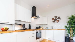Uma cozinha moderna com armários brancos, micro-ondas, forno e exaustor preto.
