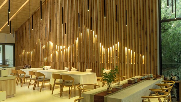 A modern restaurant with a long wooden wall, multiple tables, and chairs. - Wangshanlife Snow Garden Design Hotel (Huangshan)