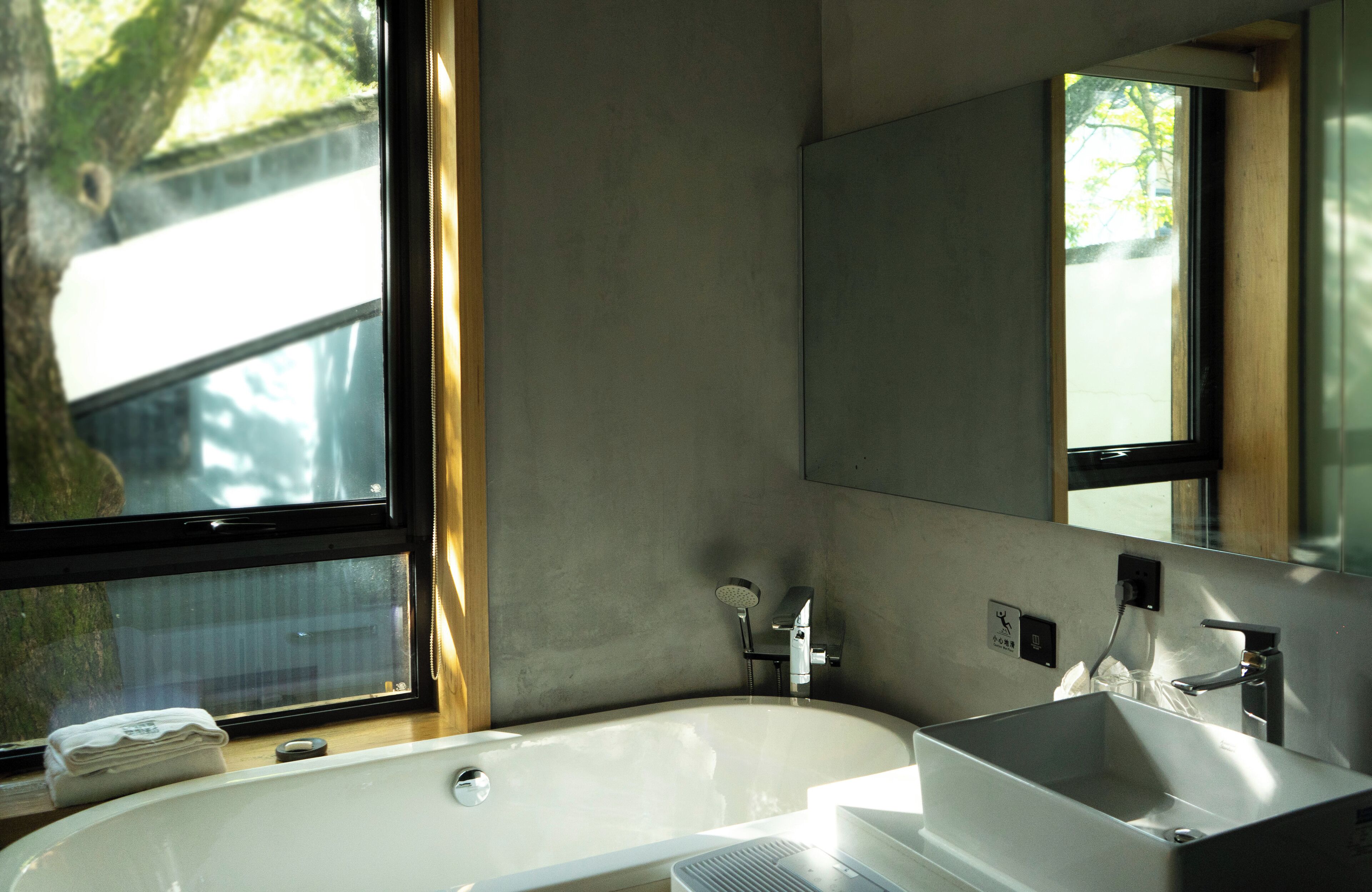 A modern bathroom with a large bathtub, a sink, and a mirror.