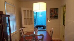 A dining area with a wooden table, four chairs, a chandelier, and a view through a door to an outdoor space. - Cozy cottage home just one mile from Augusta National. (Augusta)