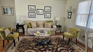 A living room with a sofa, two armchairs, a coffee table, and a patterned rug. - Cozy cottage home just one mile from Augusta National. (Augusta)