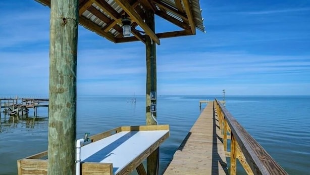 A wooden pier extending into calm water, with a bench and a small shelter at the end. - Island Time 3 Bedroom Home (Rockport)