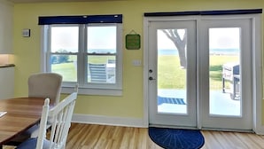 A room with a dining table, two windows, and a door leading outside. - Island Time 3 Bedroom Home (Rockport)