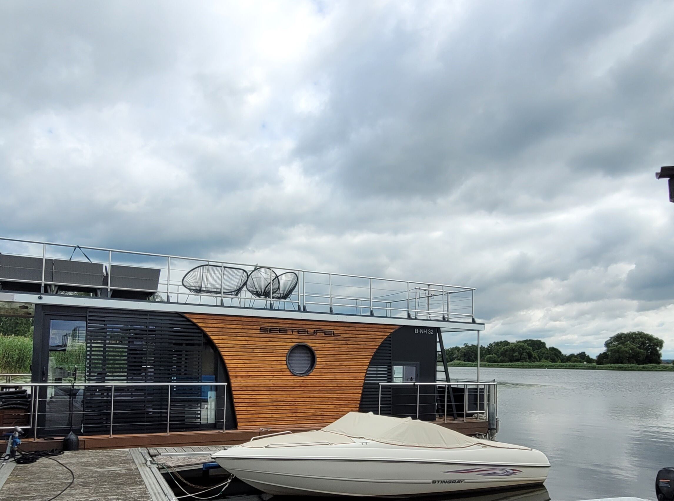 A modern boat house with a wooden facade and a covered boat docked in front.