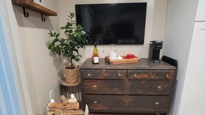 Una cocina con un mueble de madera, un televisor montado en la pared, una planta y una máquina de café.
