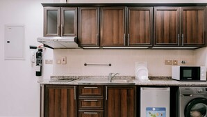 Une cuisine dotée de meubles en bois, d’un évier en acier inoxydable, d’un four à micro-ondes, d’un lave-vaisselle et d’une machine à laver.