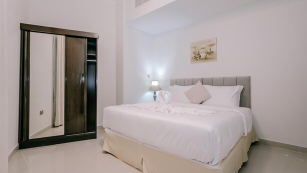 Une chambre d’hôtel avec un grand lit, une armoire, une lampe de chevet et un tableau au mur.