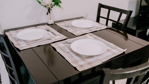 Une table à manger dressée avec des assiettes, des couverts et un vase rempli de fleurs.