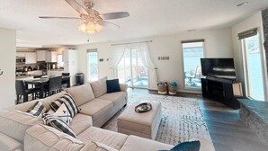 Una sala de estar moderna con un sofá, un reposapiés y un televisor de pantalla plana.