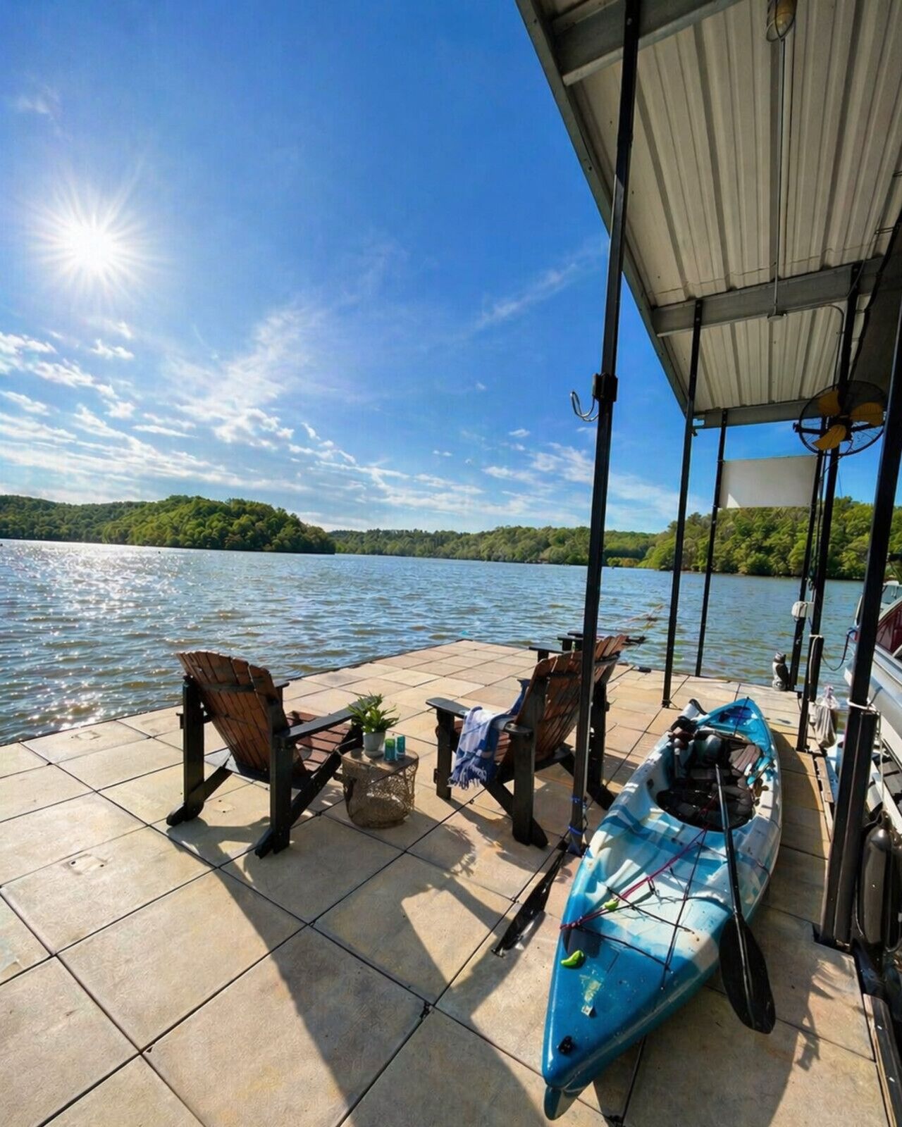 A covered dock with chairs, a kayak, and a boat.
