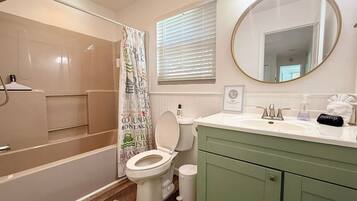 A bathroom with a bathtub, toilet, vanity, and a shower area.