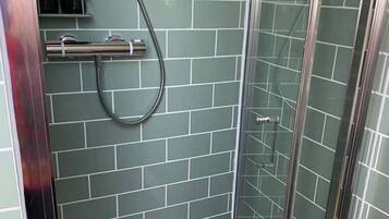 Une douche avec une porte en verre et un mur carrelé.