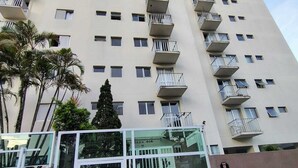 A high-rise building with multiple balconies and a gated entrance. - Apartment with pool, just a 9-minute walk from the beach! (Guarujá)