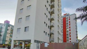 A swimming pool with a tiled deck, surrounded by high-rise residential buildings. - Apartment with pool, just a 9-minute walk from the beach! (Guarujá)